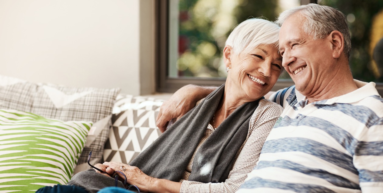 Senior couple standing in front of their home, considering a reverse mortgage in 2025